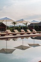 Una piscina al aire libre, sombrillas, sillones reclinables de piscina