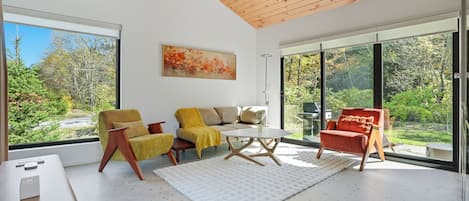 Una sala de estar moderna con un sofá, sillones, una mesa de centro y un cuadro.
