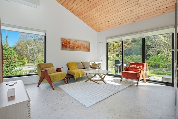 A modern living room with a sofa, armchairs, a coffee table, and a painting.