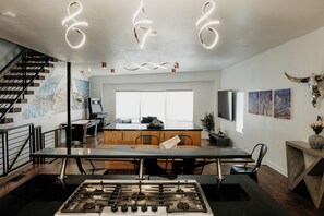 A modern kitchen with a gas stove, a dining table, and a staircase.