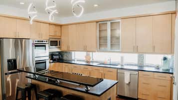 Una cocina moderna con electrodomésticos de acero inoxidable, armarios de madera y una isla central con taburetes de bar.
