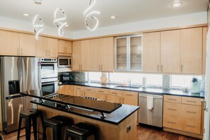 A modern kitchen with stainless steel appliances, wooden cabinets, and a central island with bar stools.