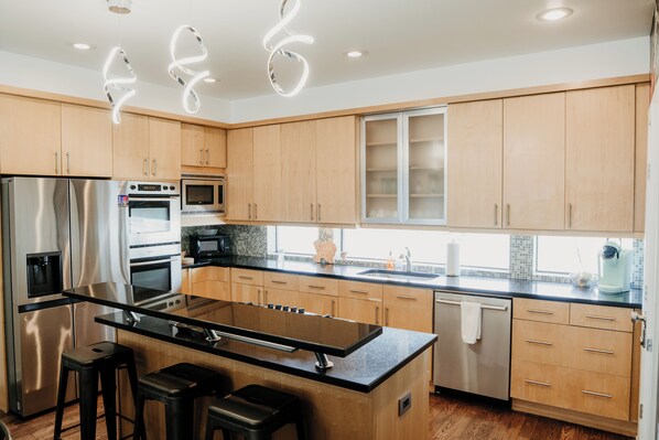 A modern kitchen with stainless steel appliances, wooden cabinets, and a central island with bar stools.