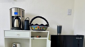 Eine Küche mit Kaffeemaschine, Wasserkocher und einem Korb auf der Arbeitsfläche.