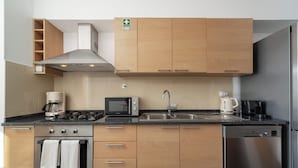 Een moderne keuken met houten kastjes, roestvrijstalen apparatuur, een magnetron, een koffiezetapparaat en een vaatwasser.