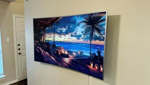 Ein großer Flachbildfernseher an der Wand, der eine Strandlandschaft bei Sonnenuntergang zeigt.