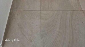 Un couloir avec une porte en bois donnant sur une chambre à coucher, où se trouvent un lit et une table de chevet.