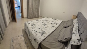 Une chambre à coucher comprenant un lit, une armoire et une porte donnant sur une autre pièce.