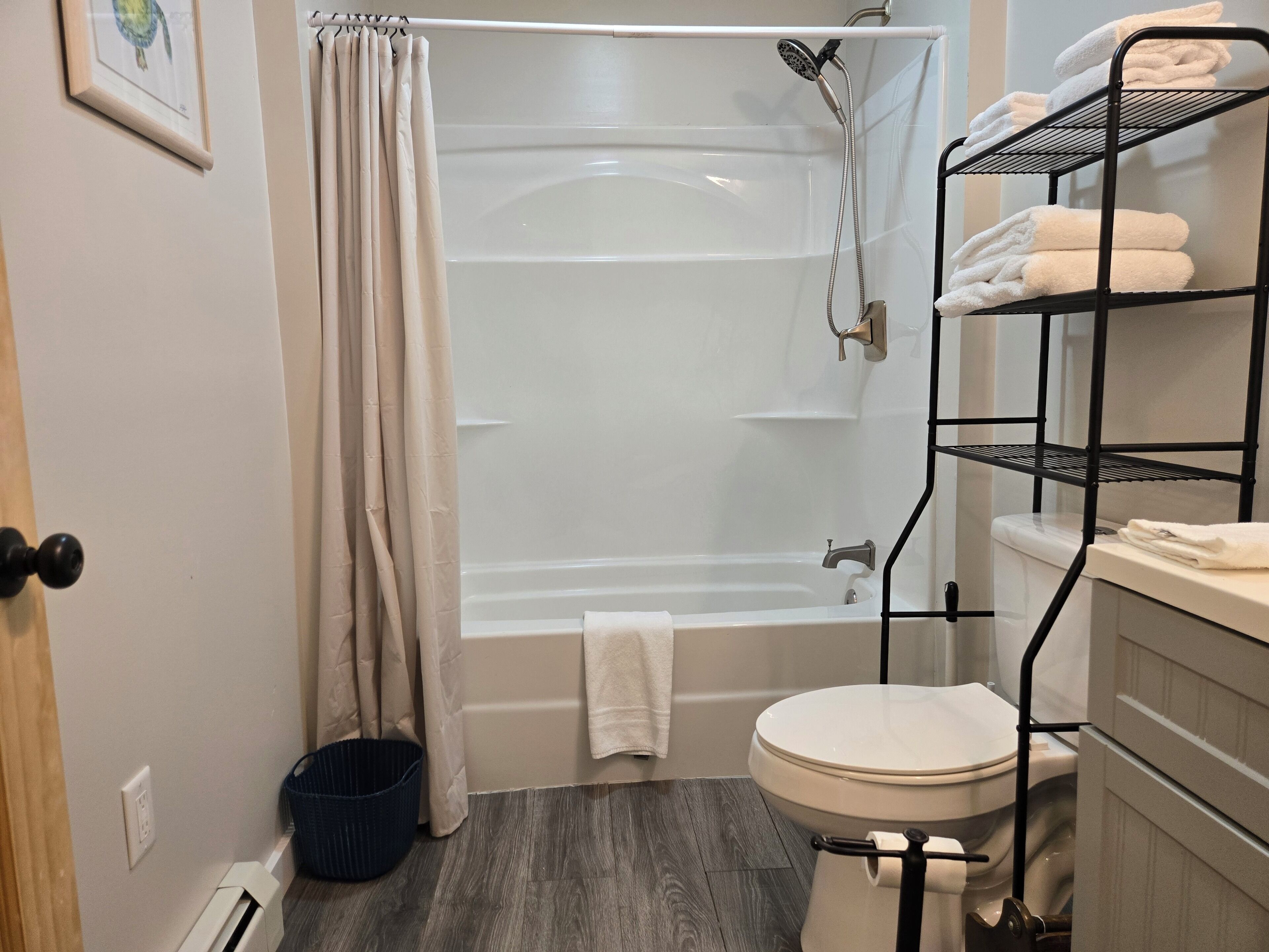 A bathroom with a bathtub, toilet, and a shelf with towels.