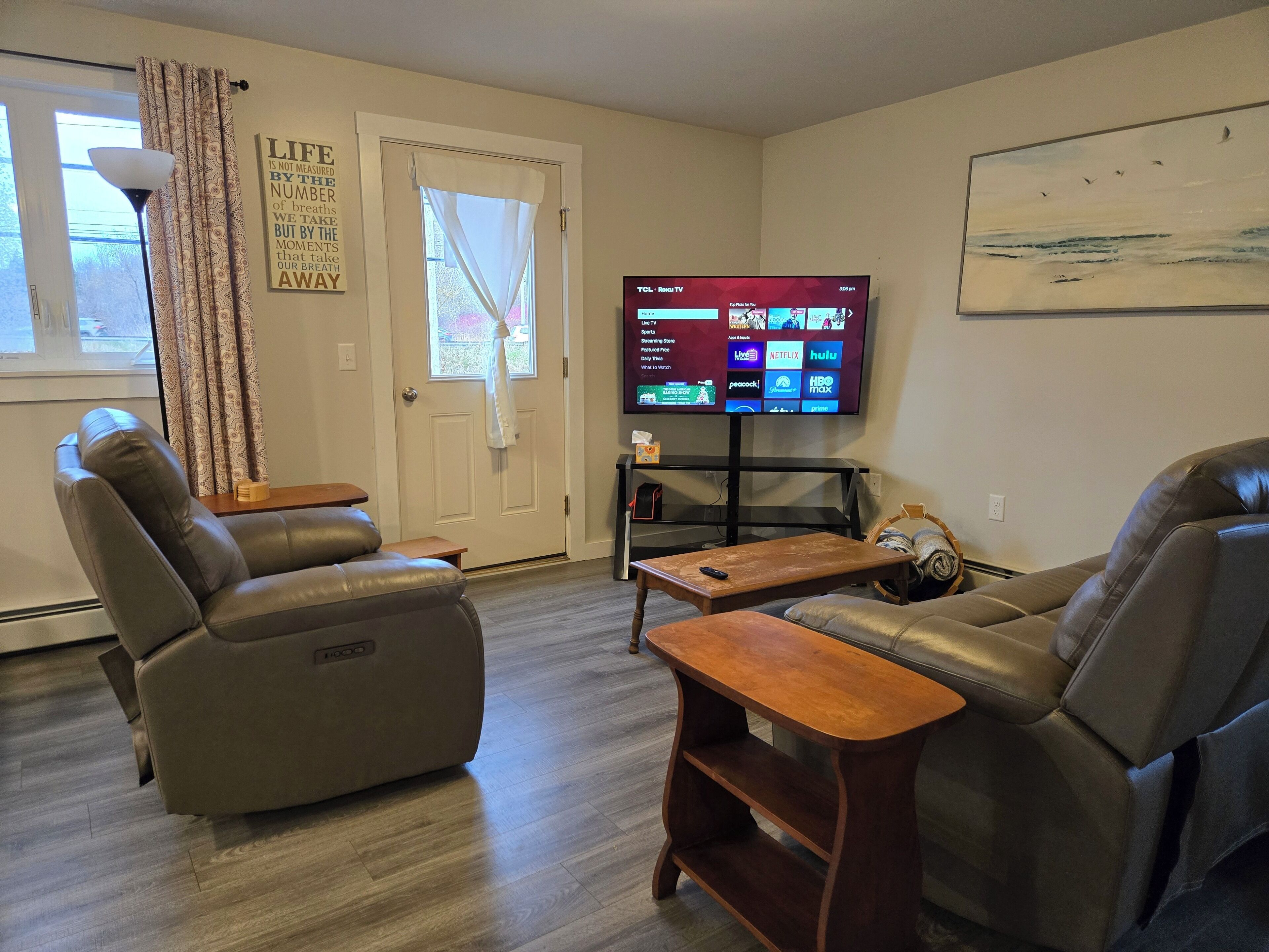 A living room with two leather recliners, a wooden coffee table, and a flat-screen TV mounted on the wall.