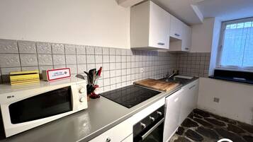 A kitchen with a microwave, stove, oven, and a stone-patterned floor.
