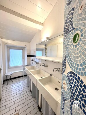 A bathroom with two sinks, a window, and a mirror.