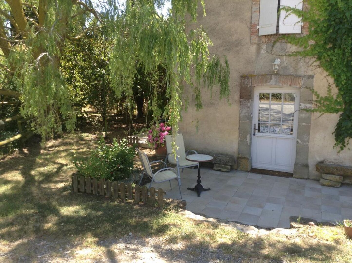 A patio area with a table and chairs, a stone wall, and a door.