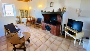 A cozy living room with a fireplace, a television, and a dining area with chairs and a table. - Gite du Cammas Blanc (VILLEPINTE)