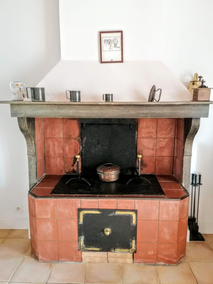 A kitchen with a tiled backsplash, a stove, and a framed picture above the counter.