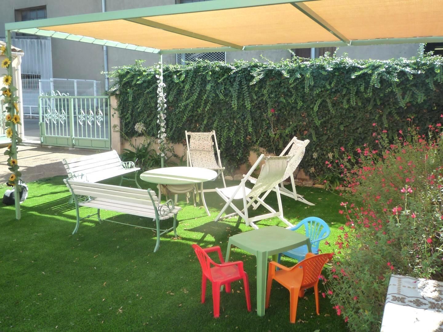 Une terrasse extérieure avec une table et des chaises, un banc et un espace abrité.