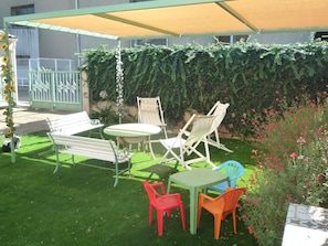An outdoor patio with a table and chairs, a bench, and a covered area. - Le jardin Ombragé - RIEUX MINERVOIS (RIEUX MINERVOIS)
