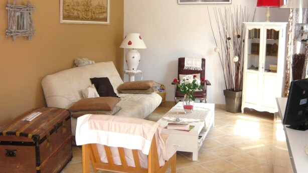 Un salon comprenant un canapé, une table basse, un fauteuil, une lampe, un meuble et une valise.