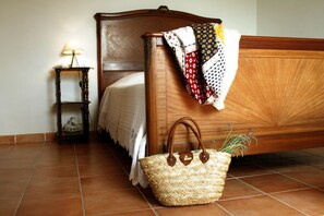 Ein Bett mit Holzkopfschild, ein Nachttisch mit Lampe und ein gewebter Korb mit Tragegriffen.