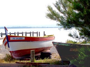Zwei Boote liegen an einem grasbewachsenen Ufer, im Hintergrund ein Holzzaun.