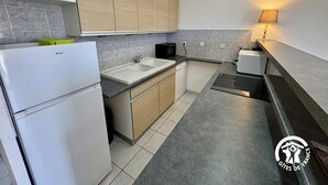 Et moderne køkken med køleskab, vask, mikroovn og en lille spiseplads.
