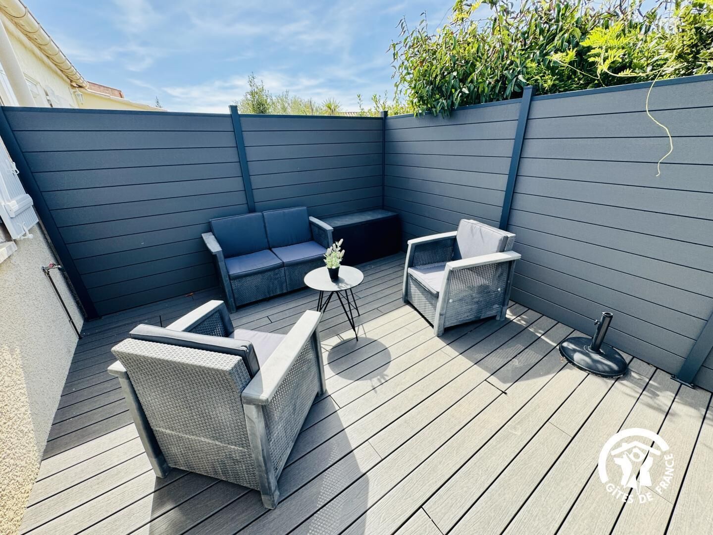 A covered outdoor seating area with a sofa, two chairs, and a small table.