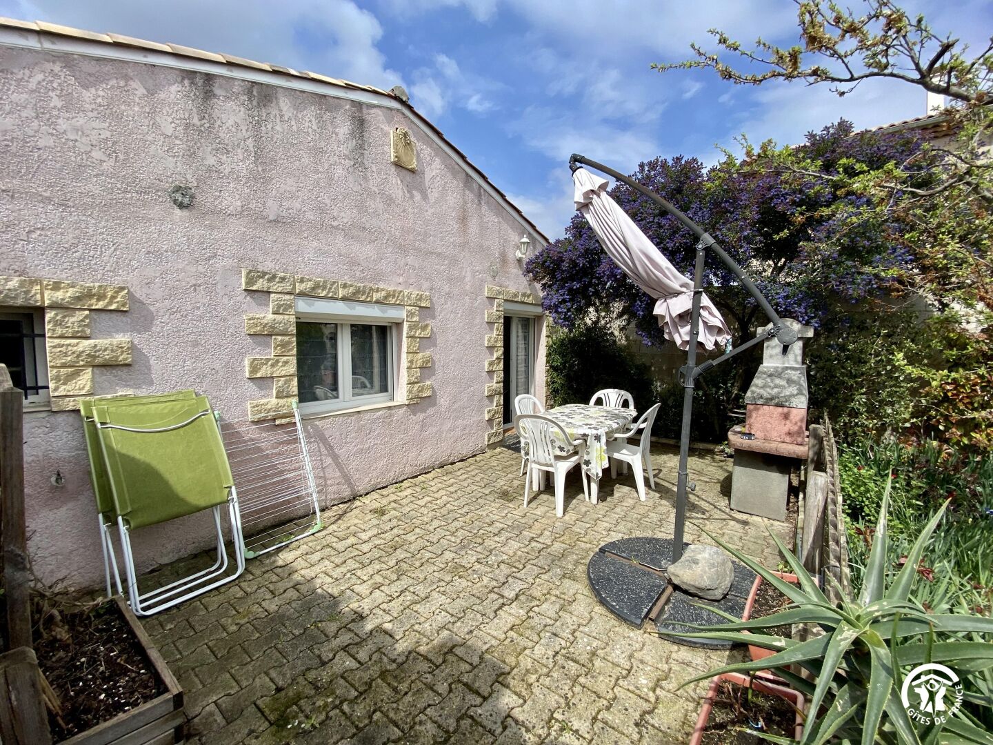 Un patio con una mesa, sillas y una estatua, incluyendo una silla plegable verde.