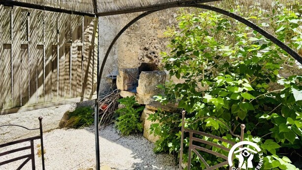 Un'area esterna rustica con un muro in pietra, una recinzione in legno e un cancello in metallo.