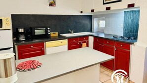 Una cucina con mobili rossi, un forno a microonde nero, una macchina da caffè e un lavello.