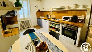 Uma cozinha compacta com mesa de jantar, fogão a gás, micro-ondas e cafeteira.