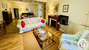 Uma sala de estar com sofá, mesa de centro, televisão e lareira.