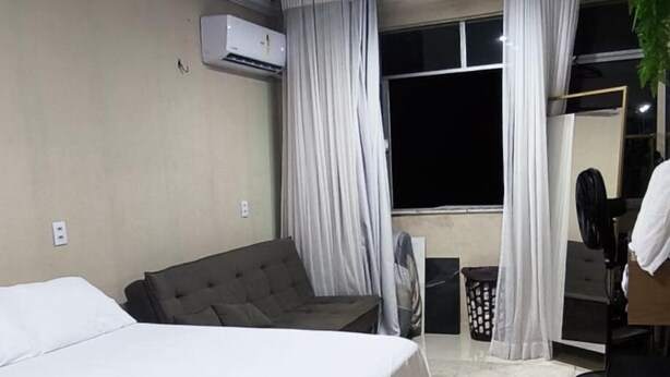 Una habitación de hotel con cama, sofá, ventilador y ventana con cortinas.