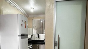 Una cocina con refrigerador, estufa y lavamanos, que da a una puerta.