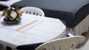 Una habitación con dos camas, una mesa de comedor con sillas, un equipo de aire acondicionado y una cortina.