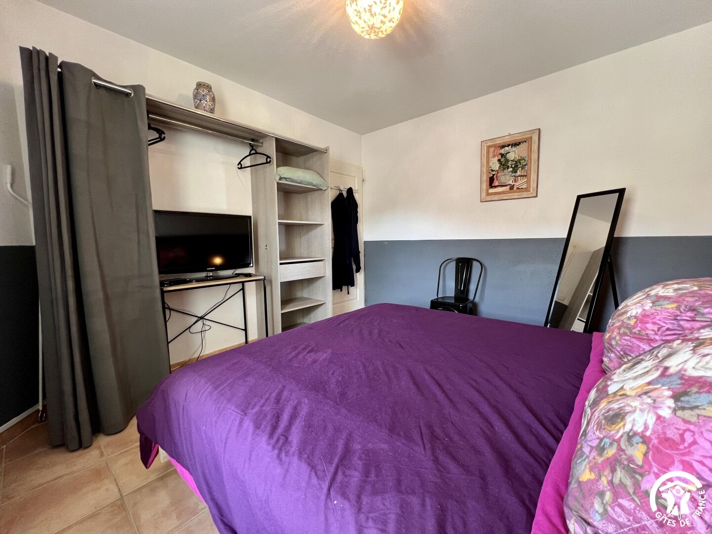 Ein Schlafzimmer mit einem Bett, einem Fernseher, einem Kleiderschrank und einem Schreibtisch.