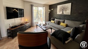 Een woonkamer met een bank, een salontafel, een televisie en een schilderij aan de muur.