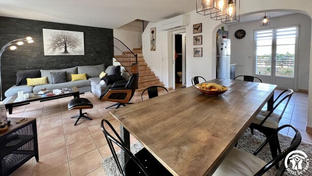 Een moderne woonkamer met een bank, salontafel en een eethoek met stoelen en een houten tafel.