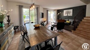 Een moderne woonkamer met een houten eettafel, een bank en een trap.