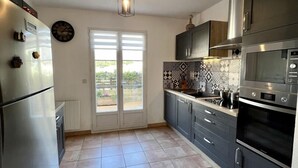 Een moderne keuken met een koelkast, oven, magnetron en een decoratieve spatwand.