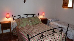 Ein Schlafzimmer mit einem Bett, zwei Nachttischen, einer Wandleuchte und einem Fenster mit Vorhang.