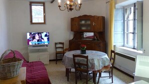 Ein Essbereich mit einer Kronleuchter, einem Holzschrank und einem Fernseher, der ein Programm zeigt.
