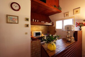 Eine Küche mit Mikrowelle, Spüle, einer Uhr und einem Fenster.
