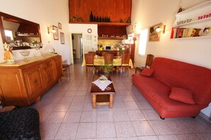 Ein Wohnzimmer mit rotem Sofa, einem Holztisch und einem Essbereich mit Stühlen und Tisch.