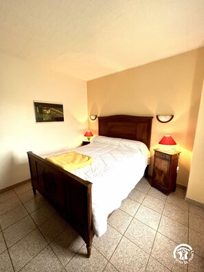 Ein Schlafzimmer mit einem hölzernen Bett, zwei Nachttischlampen, einem kleinen Nachttisch und einem Wandbild.
