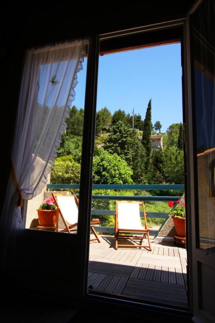 Habitación con vistas a un jardín a través de una ventana con cortinas.