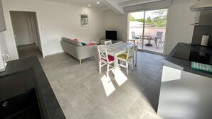 A modern kitchen with a dining area, a sofa, and a TV. - L'ancienne Cave - ROQUEFORT DES CORBIERES (ROQUEFORT DES CORBIERES)