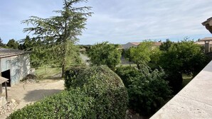 A residential area with a large tree, a concrete building, and a clear sky. - L'ancienne Cave - ROQUEFORT DES CORBIERES (ROQUEFORT DES CORBIERES)