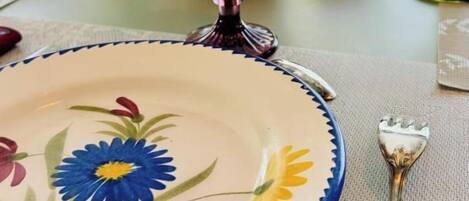 Ein Esstisch mit einer Glaskaraffe, einem Teller mit Blumenmuster und einer Gabel.