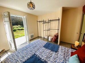 Une chambre à coucher comprenant un lit, une fenêtre, un portant à vêtements et une porte donnant sur un balcon.
