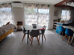 Un espace repas moderne comprenant une table et des chaises, un canapé et un coin cuisine avec des chaises bleues.